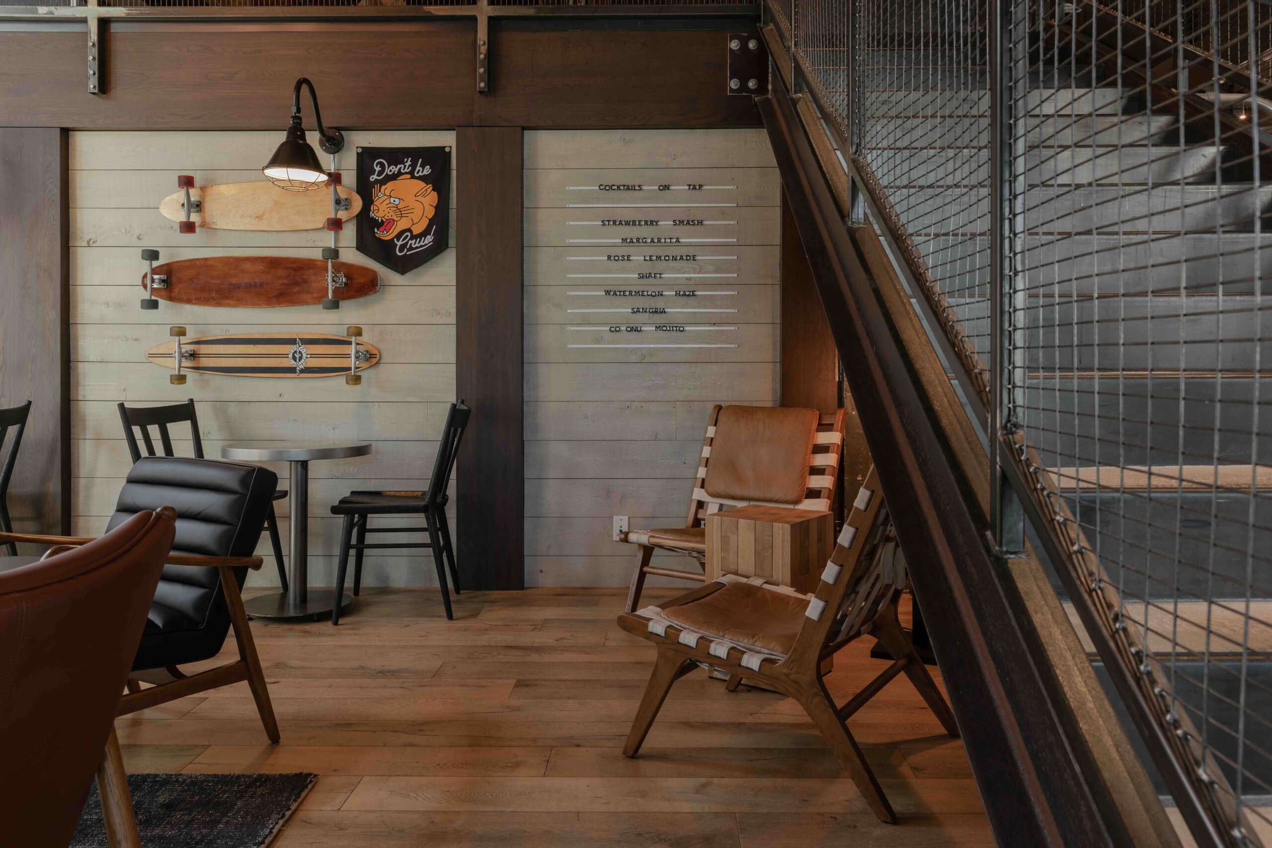 CRAFT Beer Market Modern seating area with leather and wood chairs, skateboards mounted on a wood-paneled wall, a small table, and a wall sign reflecting a casual, contemporary interior design.