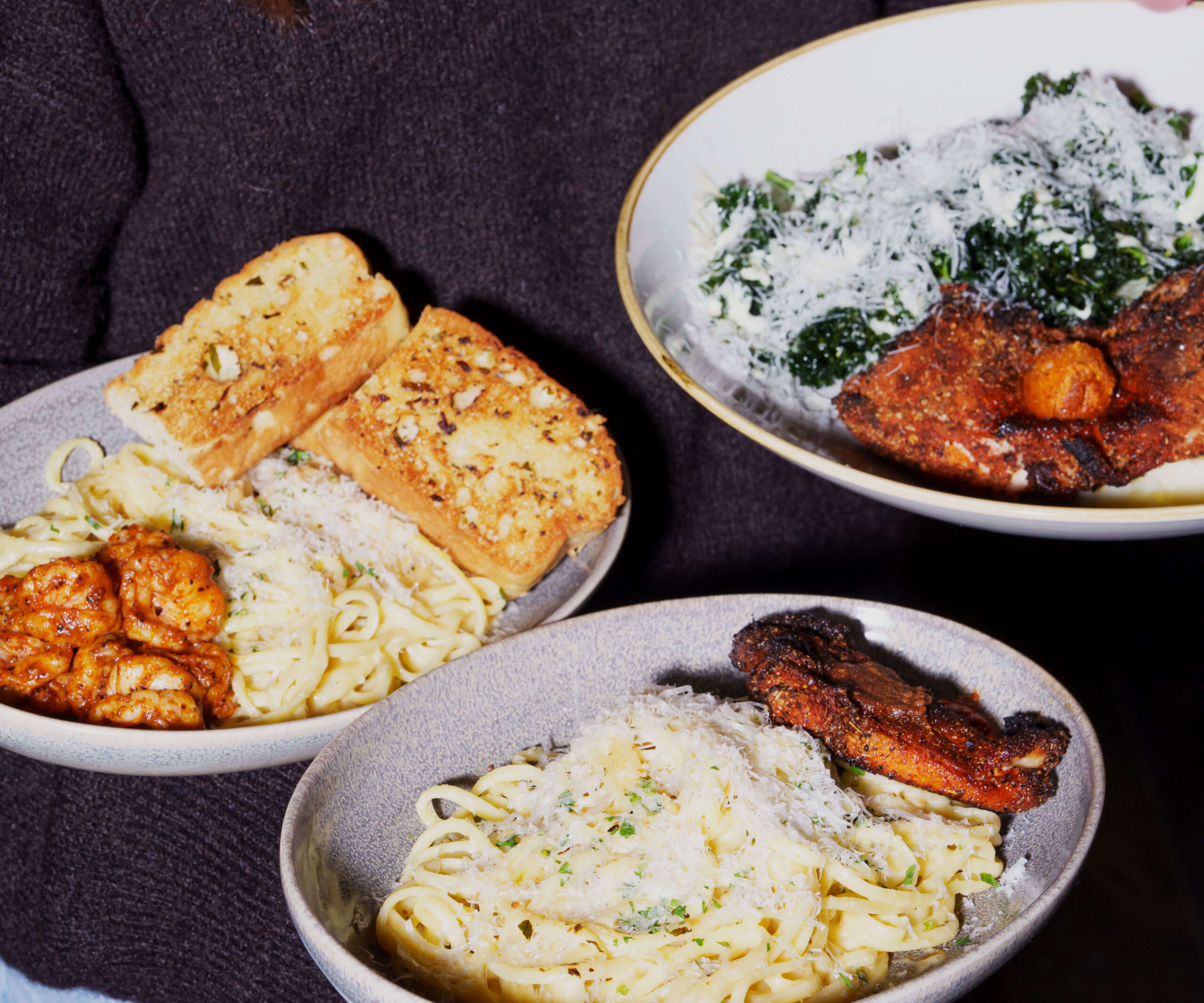 CRAFT Beer Market Three bowls of pasta topped with grilled meat or seafood, grated cheese, and herbs, served with garlic bread—perfect for group bookings at our multiple locations.