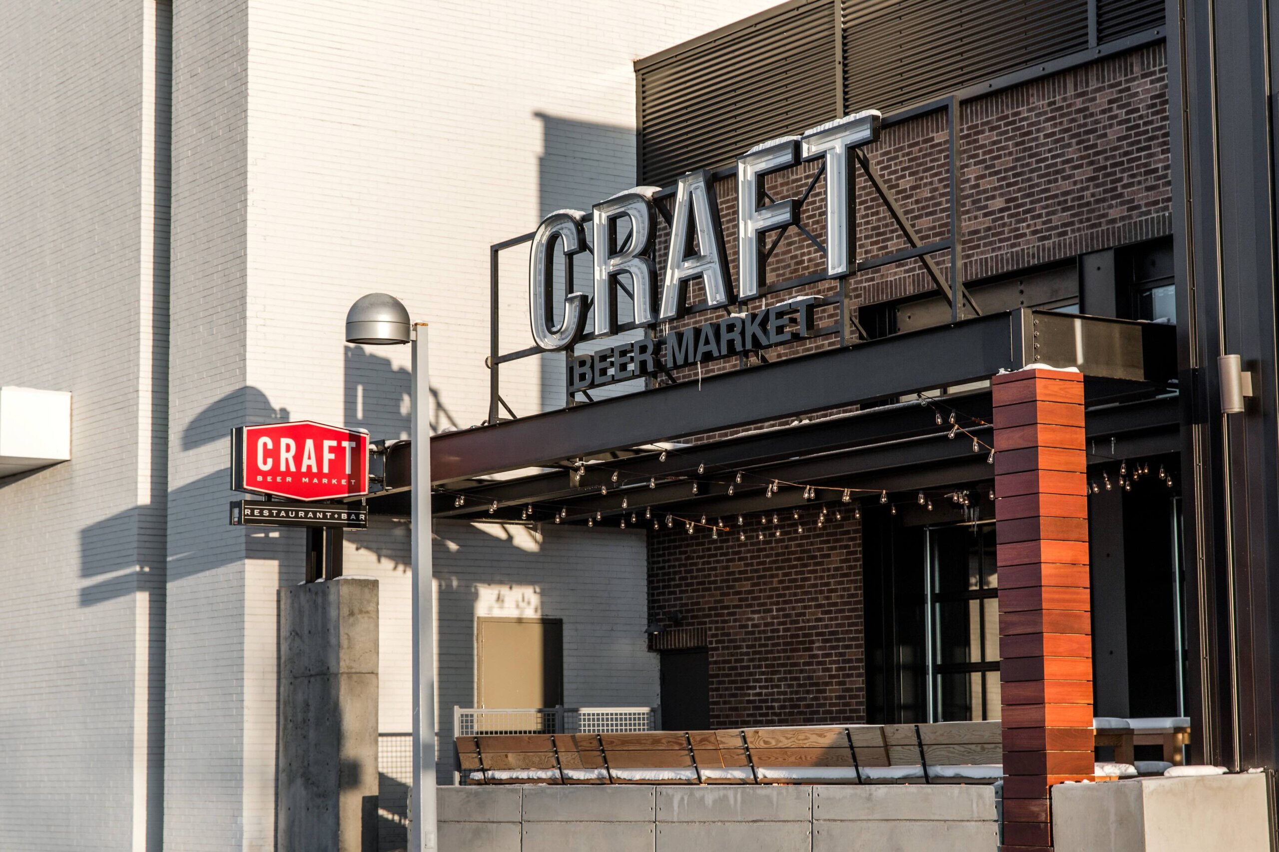 CRAFT Beer Market Exterior view of a modern building with large signs reading "CRAFT" and "CRAFT Beer Market." The facade features brick, metal, and wood accents.